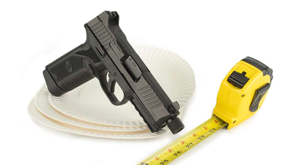 firearm with paper plates and tape measure