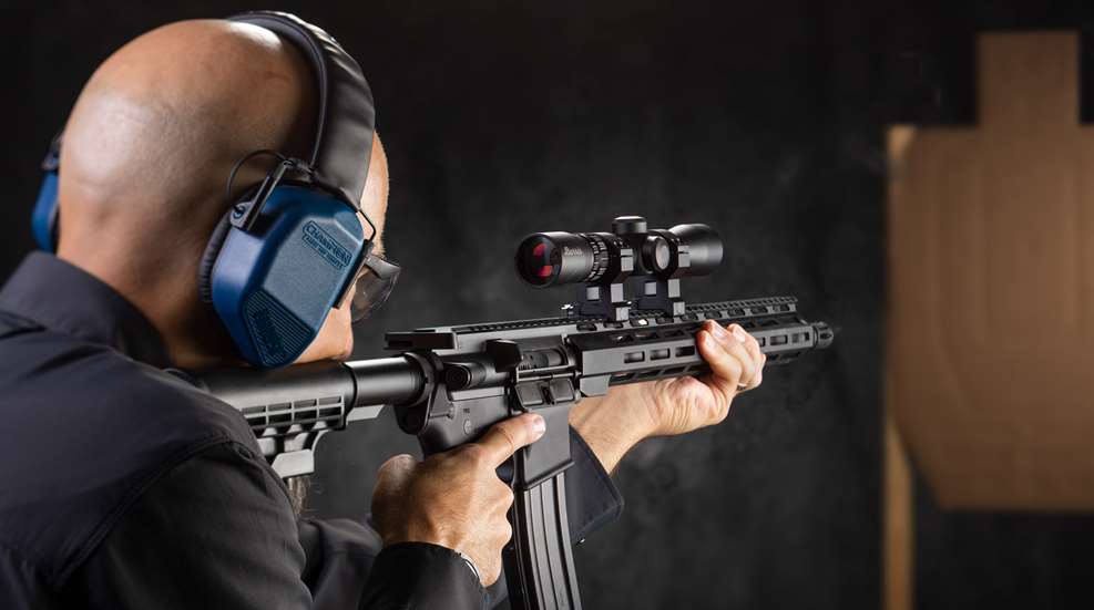 person shooting a rifle with a scope