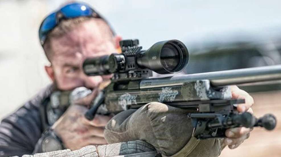 Shooter using bolt action rifle with scope