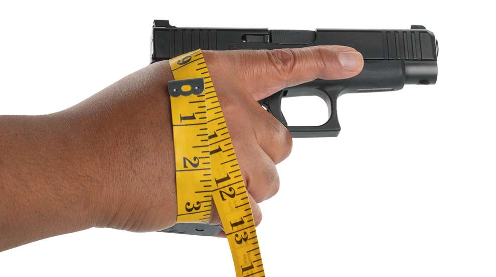hand holding pistol with tape measure