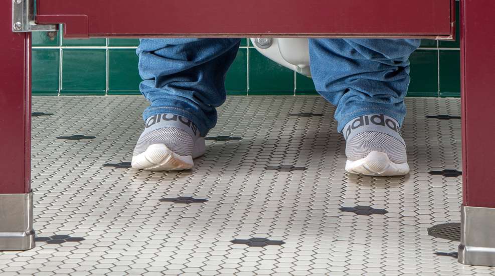 man behind door in bathroom stall
