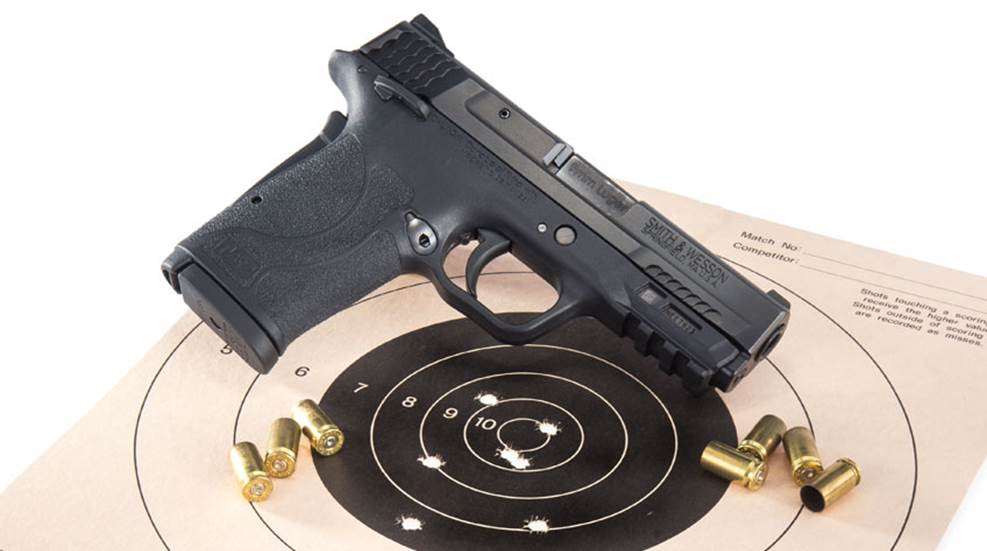 pistol on target with holes and brass