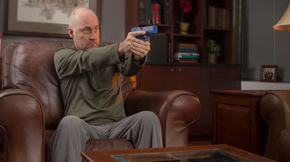 man with firearm sitting in a chair