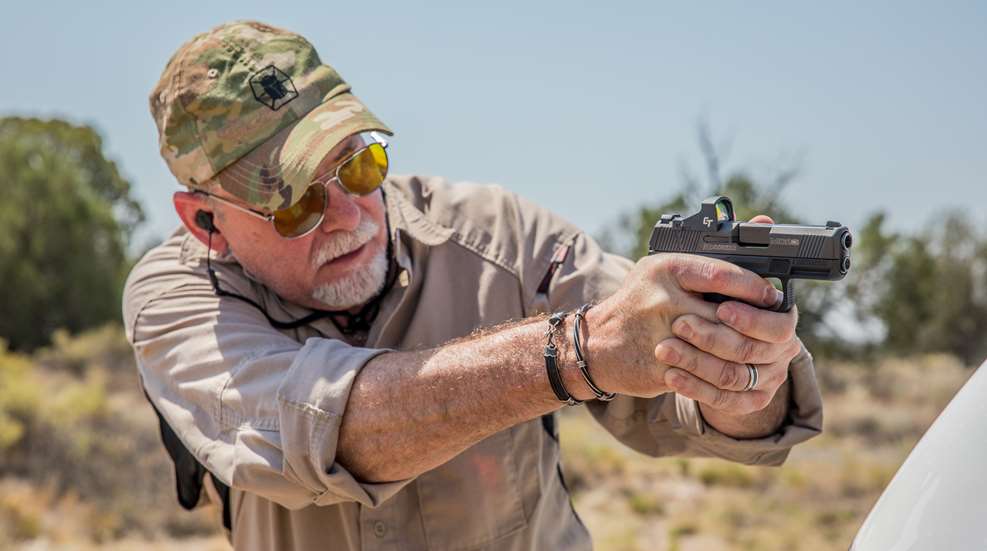 man shooting pistol with red dot